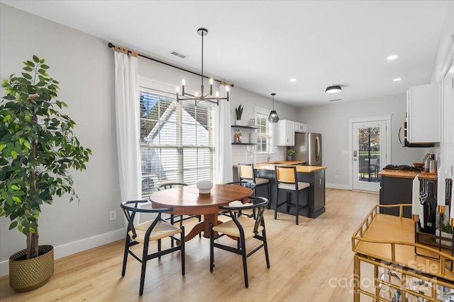 dining area featuring a notable chandelier, a healthy amount of sunlight, and light hardwood / wood-style floors