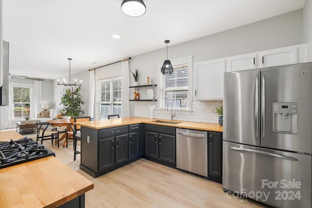 kitchen featuring decorative light fixtures, wood counters, sink, and appliances with stainless steel finishes