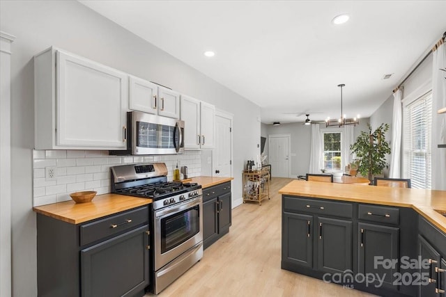 8225 Ballymore Ct, Huntersville, NC 28078 - kitchen with stainless steel appliances, wooden counters, backsplash, light wood-style flooring, and hanging light fixtures