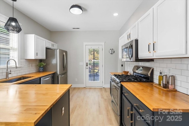 8225 Ballymore Ct, Huntersville, NC 28078 - kitchen with butcher block counters, appliances with stainless steel finishes, a sink, white cabinets, and tasteful backsplash