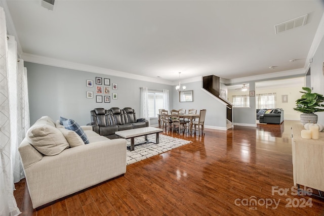 living room featuring a notable chandelier, wood-type flooring, and ornamental molding