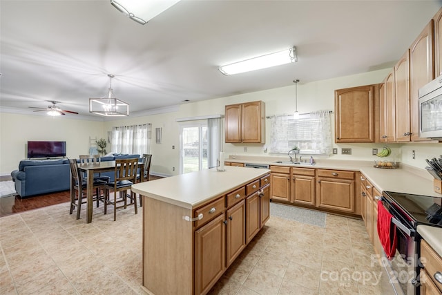 kitchen with a center island, hanging light fixtures, ceiling fan with notable chandelier, and sink