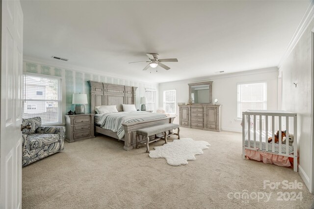 carpeted bedroom featuring ceiling fan, ornamental molding, and multiple windows