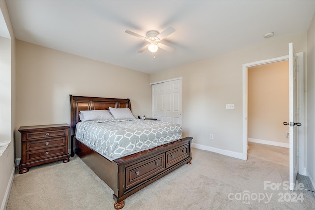 bedroom with ceiling fan, a closet, and light colored carpet