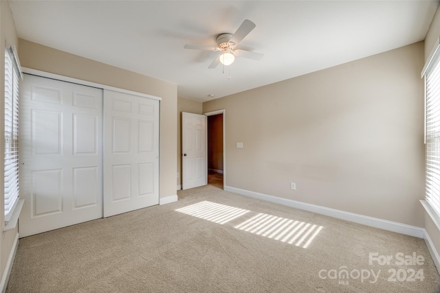 unfurnished bedroom with a closet, ceiling fan, and light colored carpet