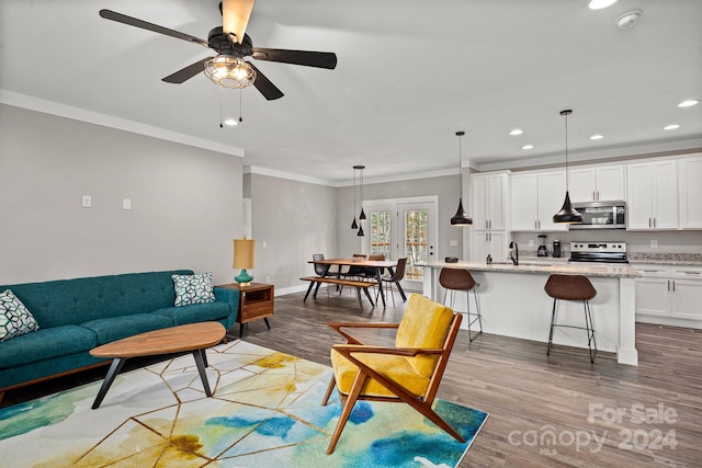 living room with hardwood / wood-style floors, ornamental molding, ceiling fan, and sink