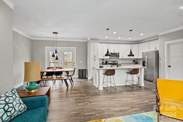 living room featuring wood-type flooring, ornamental molding, and sink