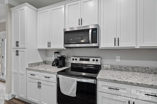 kitchen with light stone countertops, dark wood-type flooring, white cabinets, and stainless steel appliances