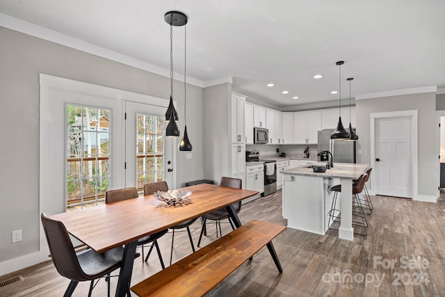 dining room featuring sink, crown molding, and light hardwood / wood-style floors