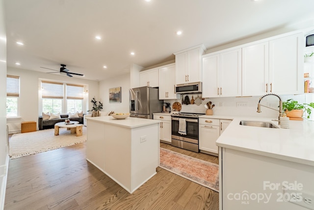 kitchen with a sink, a center island, light wood finished floors, and stainless steel appliances