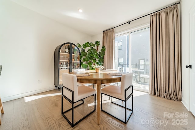 dining space featuring light wood-type flooring and baseboards