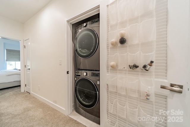 laundry area with carpet flooring, baseboards, laundry area, and stacked washing maching and dryer