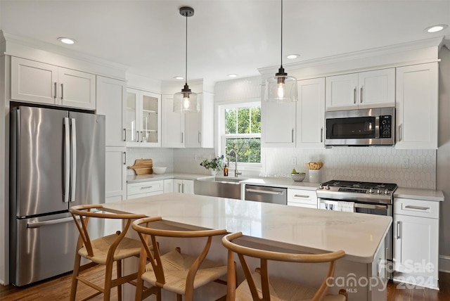 kitchen with appliances with stainless steel finishes, dark hardwood / wood-style flooring, a breakfast bar, sink, and white cabinetry