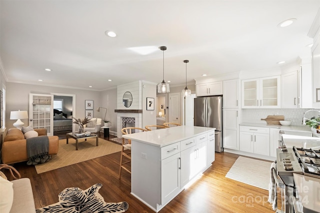 kitchen featuring white cabinets, sink, hanging light fixtures, light hardwood / wood-style flooring, and appliances with stainless steel finishes