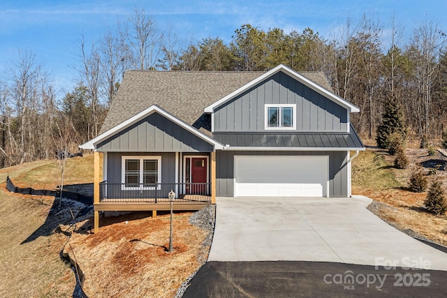 view of front facade with metal roof, driveway, a shingled roof, and a standing seam roof