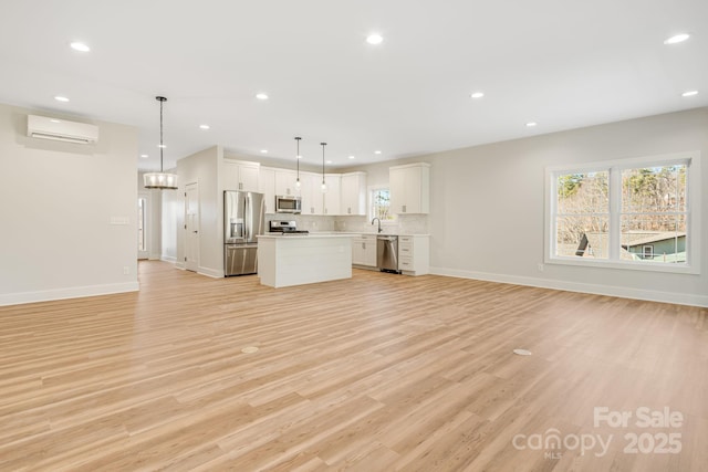 unfurnished living room featuring light wood-type flooring, a wall unit AC, and a wealth of natural light