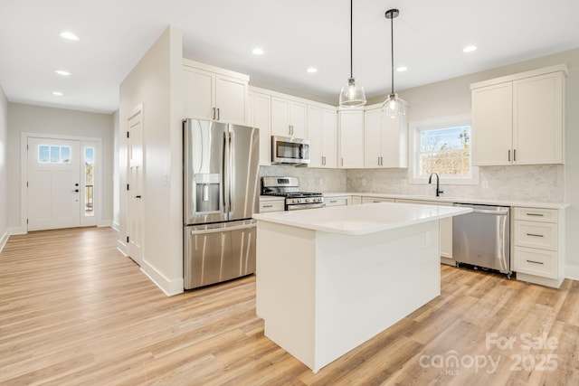 kitchen with appliances with stainless steel finishes, light countertops, decorative light fixtures, and a center island