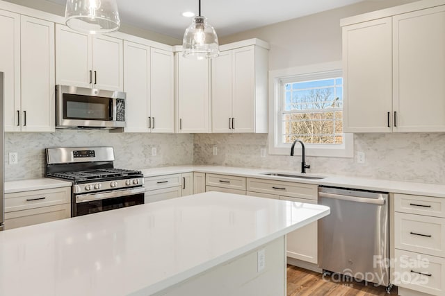 kitchen featuring stainless steel appliances, light countertops, a sink, and white cabinetry