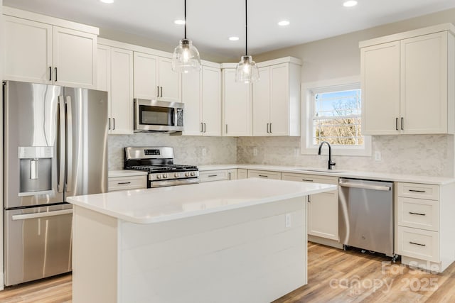 kitchen with stainless steel appliances, a sink, white cabinets, and a center island