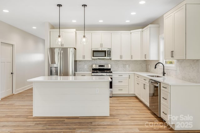 kitchen featuring a center island, pendant lighting, stainless steel appliances, light countertops, and white cabinets