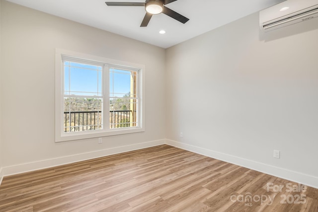 empty room featuring light wood-style floors, a wall unit AC, baseboards, and a ceiling fan