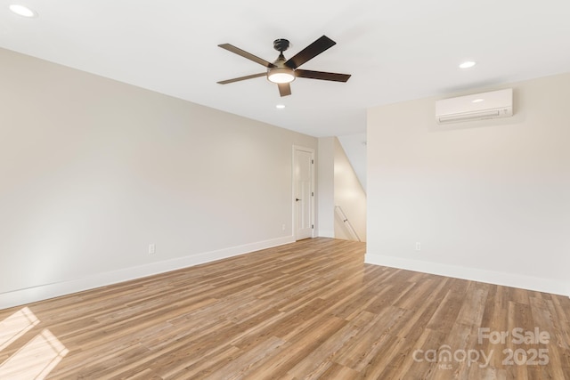 empty room with recessed lighting, light wood-style flooring, baseboards, and a wall mounted AC