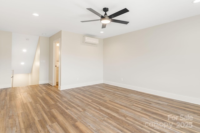 unfurnished room with light wood finished floors, baseboards, a wall unit AC, ceiling fan, and recessed lighting