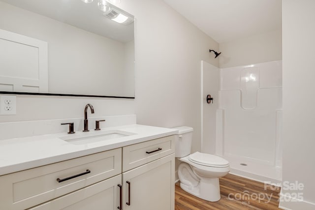 bathroom with visible vents, toilet, wood finished floors, walk in shower, and vanity