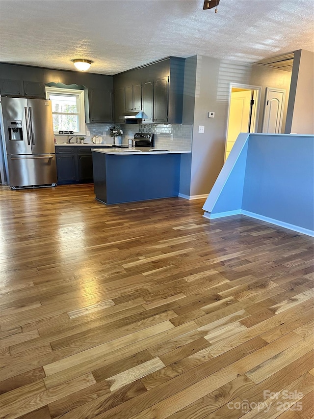 kitchen with range with electric cooktop, stainless steel fridge, light wood-type flooring, and kitchen peninsula