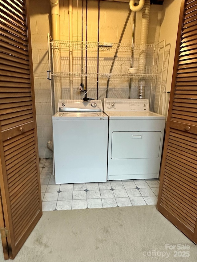 clothes washing area featuring light tile patterned floors and washing machine and dryer