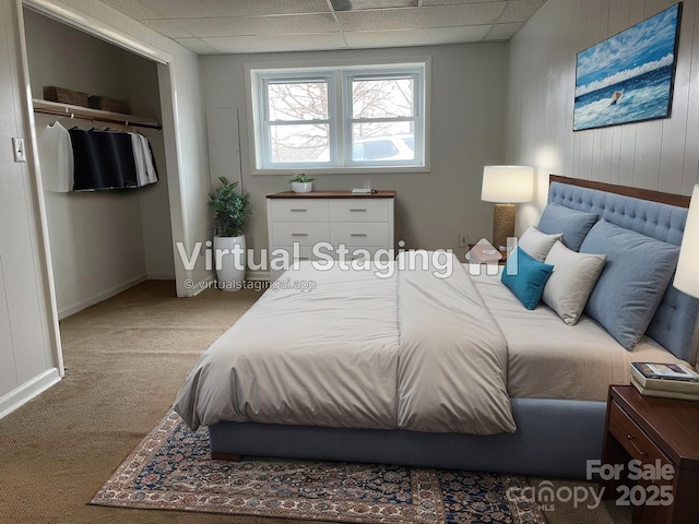 bedroom featuring wooden walls, carpet flooring, a closet, and a drop ceiling