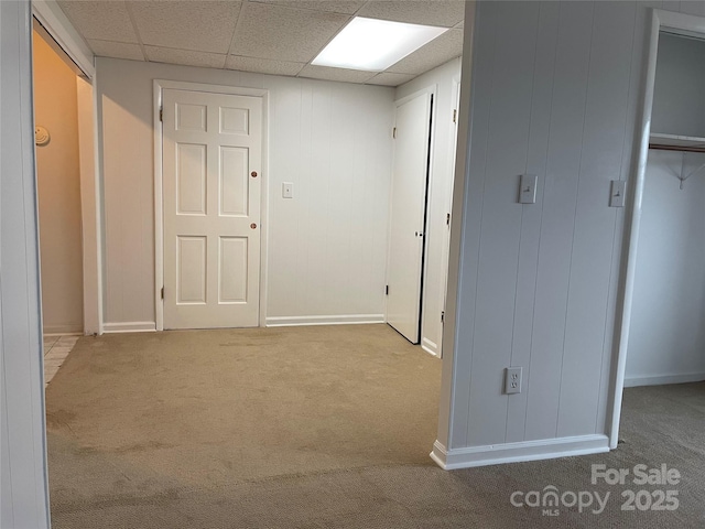 hall with a paneled ceiling and carpet