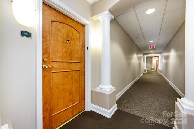 hall with dark carpet and a drop ceiling