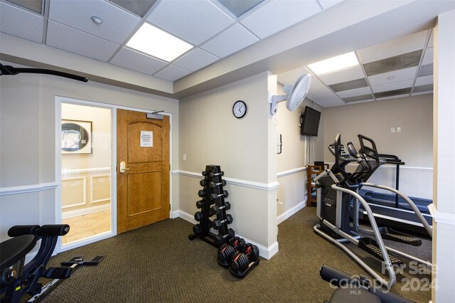 exercise area featuring a paneled ceiling and dark carpet