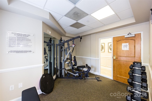 workout room featuring carpet flooring and a paneled ceiling