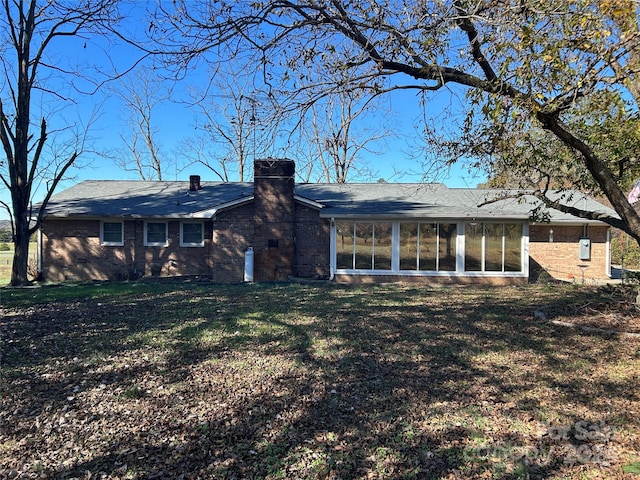 rear view of property featuring a lawn and a sunroom