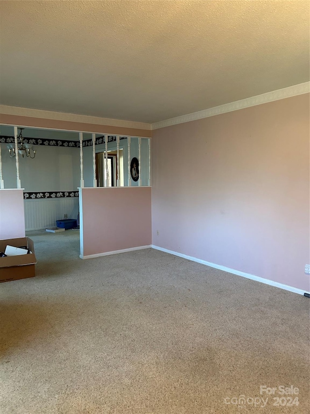 empty room with carpet, a textured ceiling, and crown molding