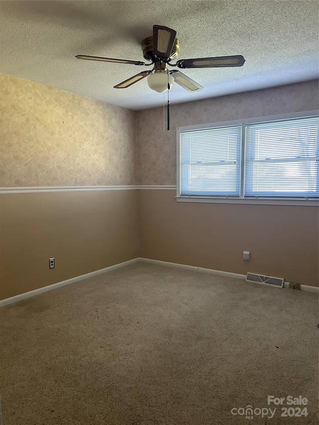 spare room featuring a textured ceiling, ceiling fan, and carpet floors