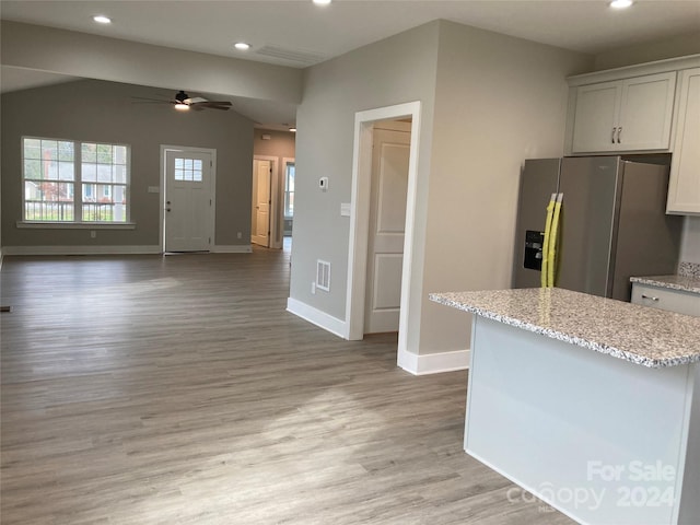 kitchen featuring white cabinetry, light stone countertops, ceiling fan, stainless steel fridge, and light hardwood / wood-style floors