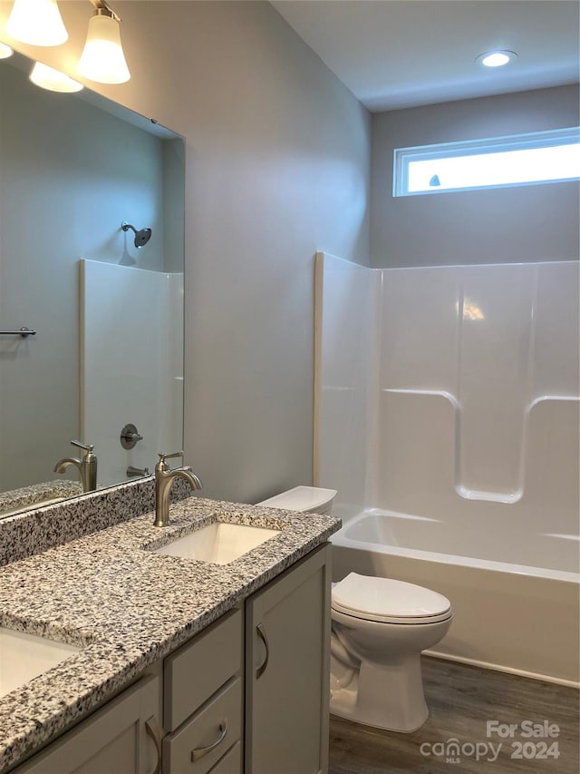 full bathroom featuring shower / washtub combination, vanity, wood-type flooring, and toilet