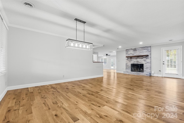 unfurnished living room featuring a fireplace, light hardwood / wood-style flooring, ceiling fan, and crown molding