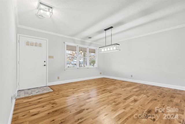 unfurnished dining area with a textured ceiling, light hardwood / wood-style flooring, and crown molding