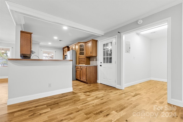 kitchen featuring electric panel, stainless steel refrigerator, light hardwood / wood-style flooring, and ornamental molding