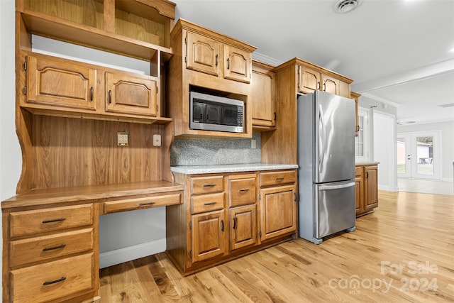 kitchen featuring decorative backsplash, appliances with stainless steel finishes, ornamental molding, built in desk, and light hardwood / wood-style flooring