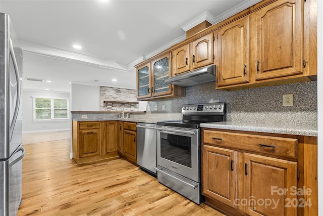 kitchen with ventilation hood, crown molding, light hardwood / wood-style flooring, appliances with stainless steel finishes, and tasteful backsplash