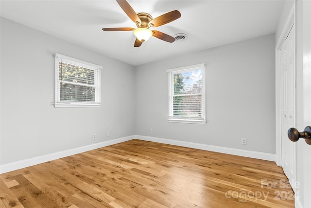 unfurnished room featuring hardwood / wood-style flooring, a wealth of natural light, and ceiling fan