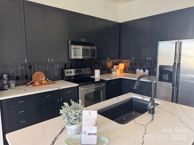 kitchen featuring backsplash, sink, light stone counters, and stainless steel appliances