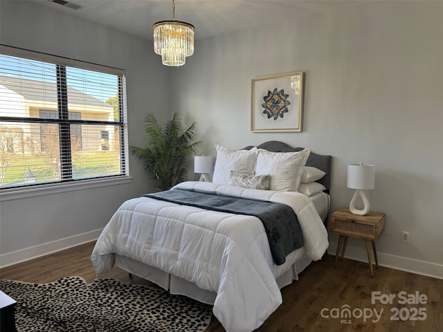 bedroom featuring dark wood-type flooring, multiple windows, and a chandelier