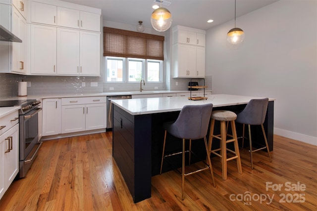 kitchen featuring white cabinetry, decorative light fixtures, stainless steel appliances, and a center island