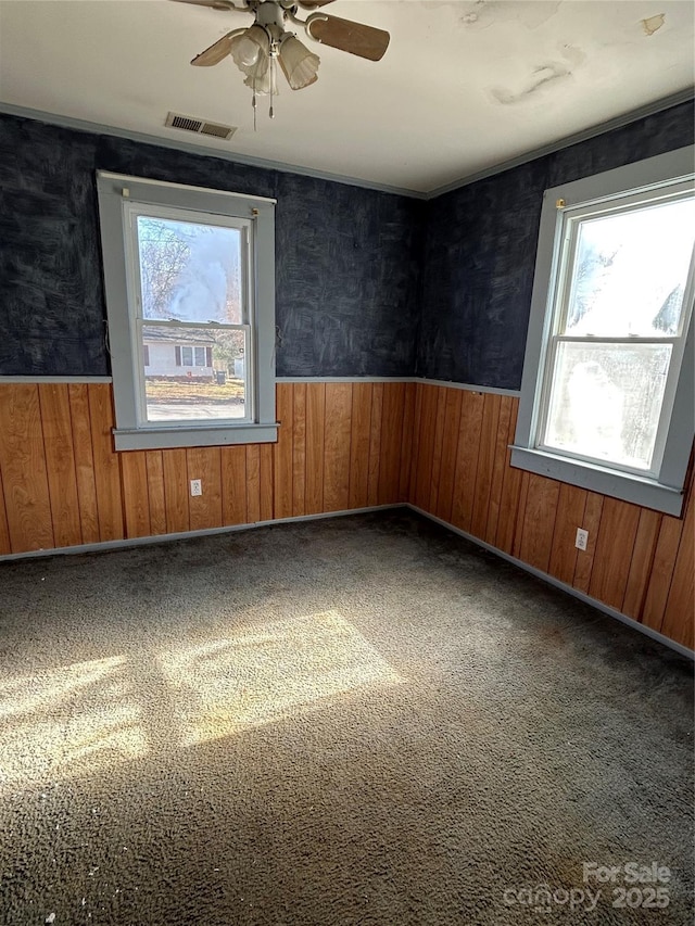 carpeted spare room with ceiling fan and wooden walls